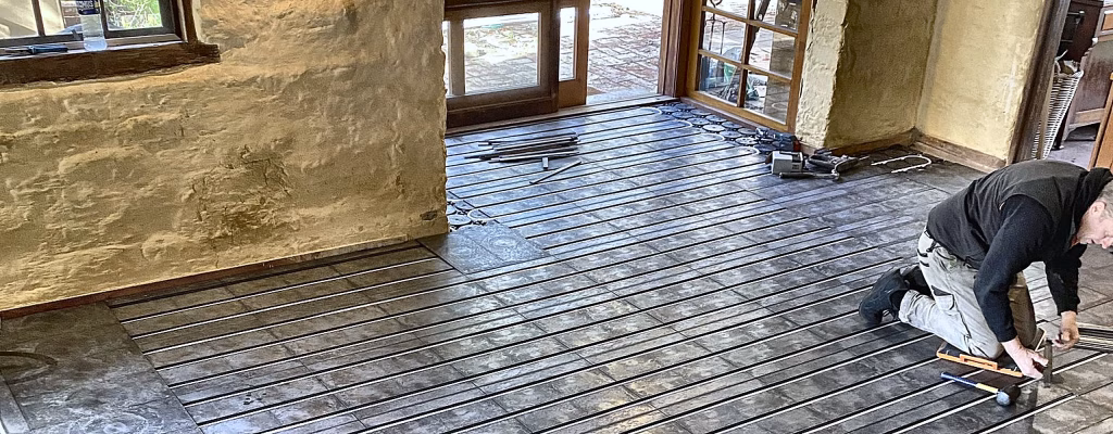Installer pressing heating pipe into HOYA Ondol panels laid over the existing floor of a stone cottage in Daylesford, Victoria