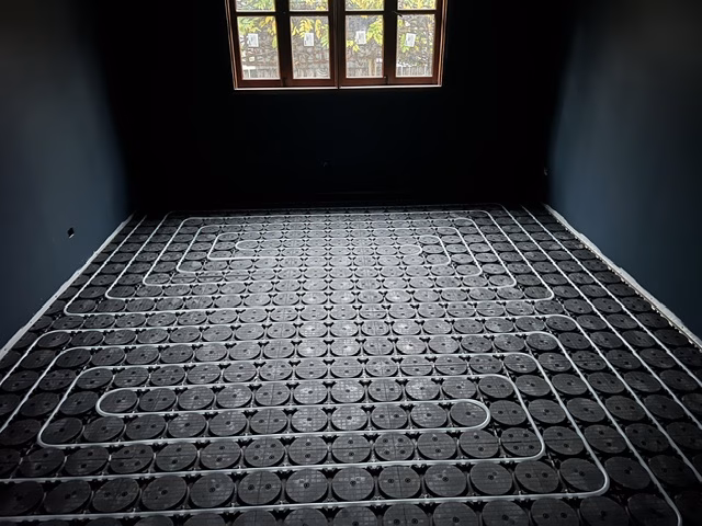 Bedroom in the O'Connor ACT renovation with white hydronic pipe laid in a serpentine loop pattern across black HOYA Ondol panels