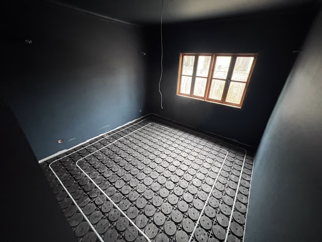 Bedroom in the O'Connor ACT renovation with white hydronic pipe laid in a loop around the room in black HOYA Ondol panels