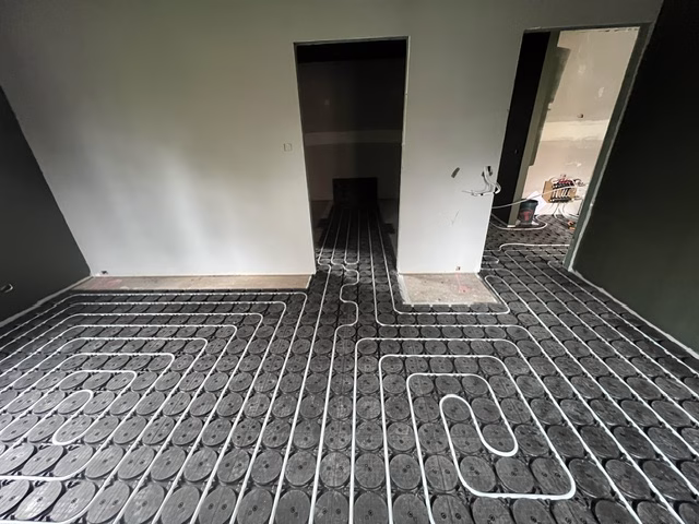 Heating pipe laid in serpentine loops through HOYA Ondol panels across an open-plan area
