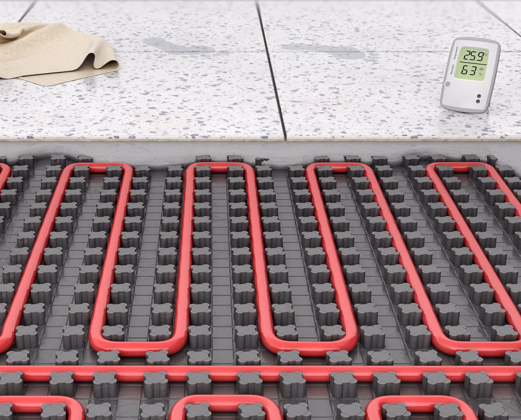 Cutaway of electric floor heating under tiles: a red heating cable woven through a studded membrane on the subfloor, with tiles bedded on top
