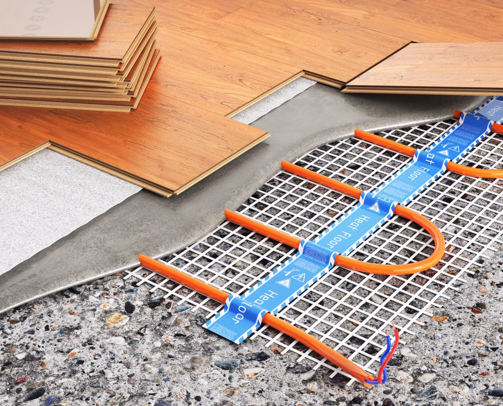 Cutaway of electric floor heating under a floating floor: a heating cable mat on a concrete slab, covered by a thin levelling layer and underlay, with laminate boards being laid on top