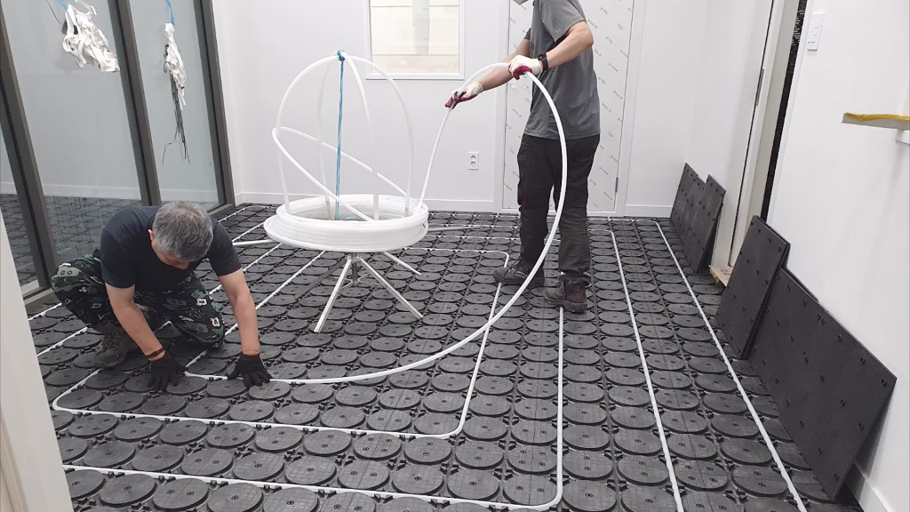 Installers pressing heating pipe into HOYA Ondol panels
